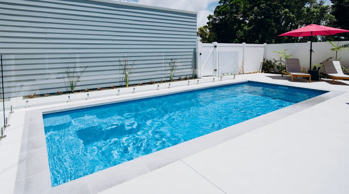 A Kiwi Dream 8 fibreglass pool set into pale paving