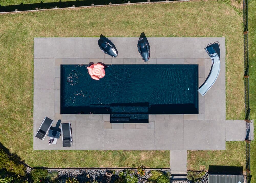 Aerial view of a dark-shell Kiwi Estate 10 pool with a slide and loungers