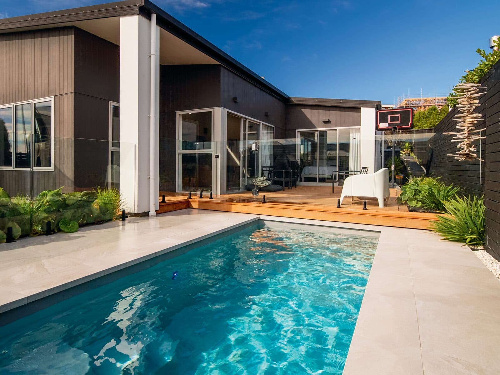A Kiwi Urban 5 plunge pool beside a timber deck and a modern home